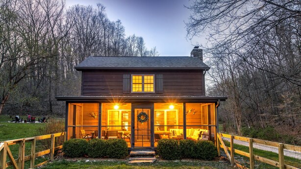 A wooden house with a porch, a front door, and a small garden area. - Welcome to Brooks Run - A 1920s Cabin in Beautiful Brown County, Indiana (Nashville)