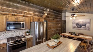 A rustic kitchen with wooden cabinets, stainless steel appliances, a wooden island, and a ceiling fan. - Welcome to Brooks Run - A 1920s Cabin in Beautiful Brown County, Indiana (Nashville)