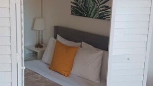 Ein Schlafzimmer mit einem Bett, einem Nachttisch, einer Lampe und einer Wandpflanze.