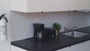 Eine Küche mit schwarzem Arbeitsplatz, einer Kaffeemaschine, einem Toaster, einer Spüle und einem Feuerlöscher.