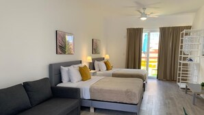 Habitación de hotel con cama, sofá, escritorio y balcón.