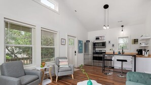 Una cocina moderna con electrodomésticos de acero inoxidable, una encimera blanca y taburetes de bar.