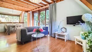 Una sala de estar acogedora con un sofá, una mesa de comedor y un televisor montado en la pared.