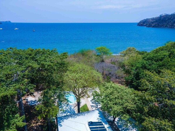 Vista costera con mar azul turquesa, una isla rocosa y abundante vegetación verde.