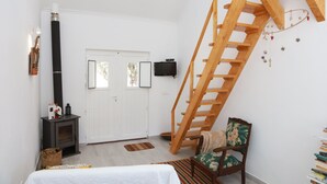 A bedroom with a wooden ladder, a fireplace, a bed, and a chair. - Monte Típico Alentejano (Escoural)