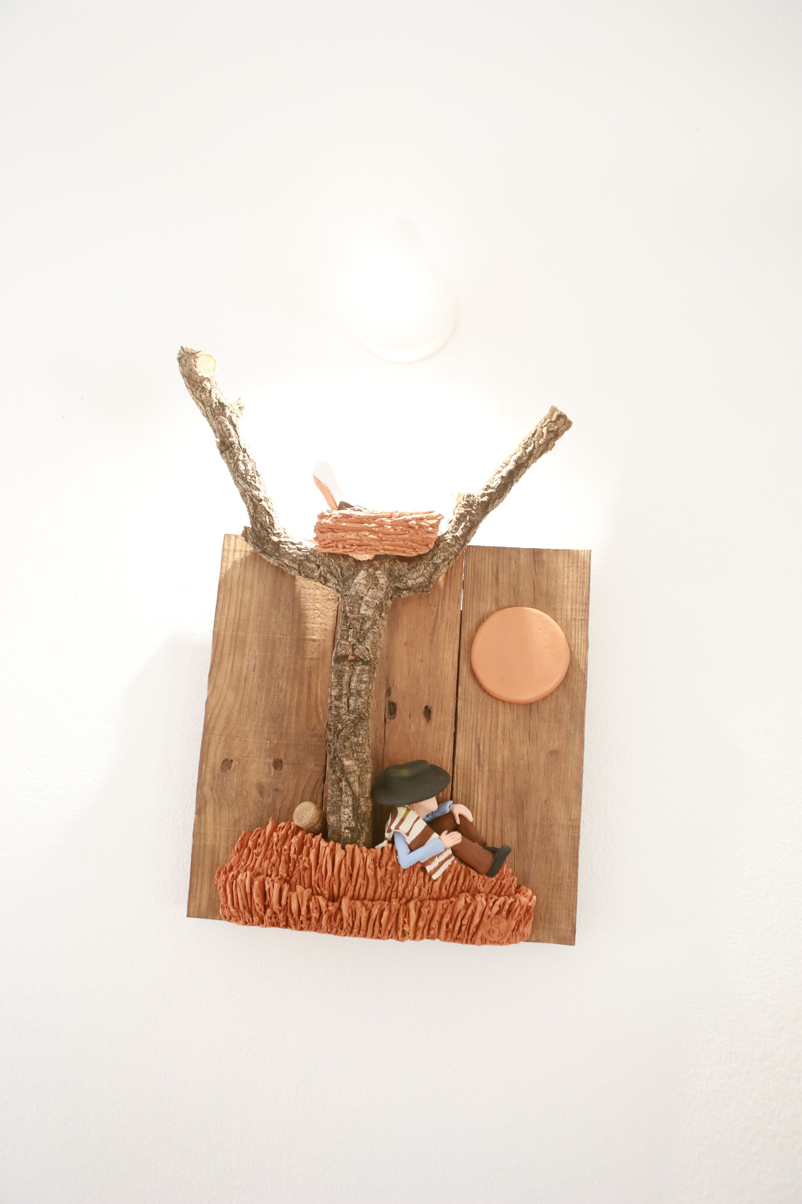 Eine Holzhütte mit einem Ast, einer kleinen Figur und einem runden, orangefarbenen Objekt.