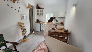 A cozy, well-lit room with a dining area, a small kitchen, and a bookshelf. - Monte Típico Alentejano (Escoural)