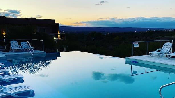 Une piscine à débordement avec des chaises longues et une vue sur le paysage.