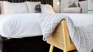 A bedroom with a bed, a bedside lamp, a wall-mounted TV, and a painting. - Kaka Point Luxury Spa Accommodation (Kaka Point)