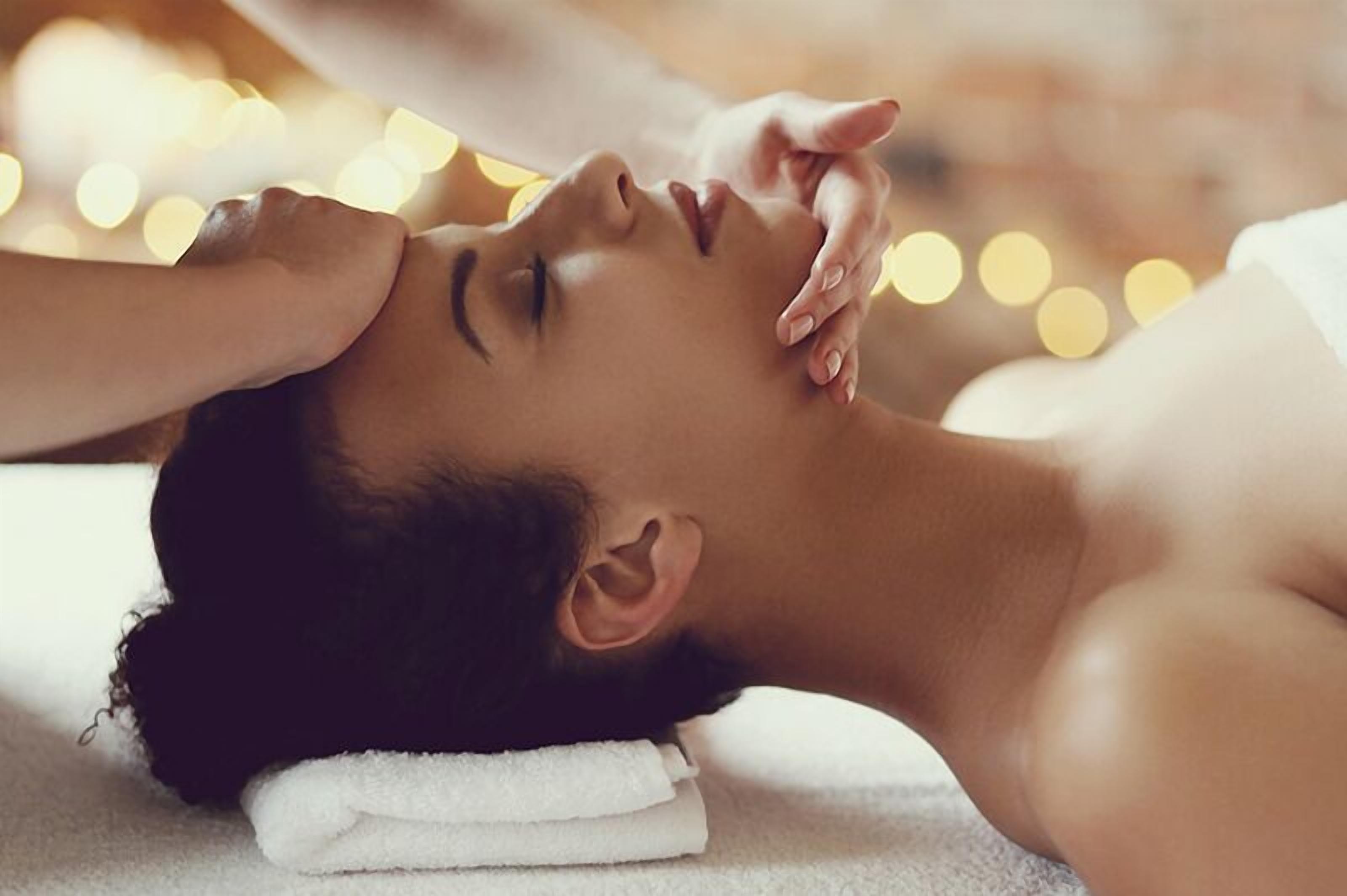 Une personne allongée, une serviette sur la tête, qui reçoit un massage.