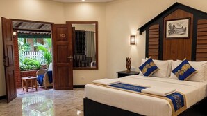 A bedroom with a large bed, a wooden headboard, a nightstand, and a door leading to a balcony.