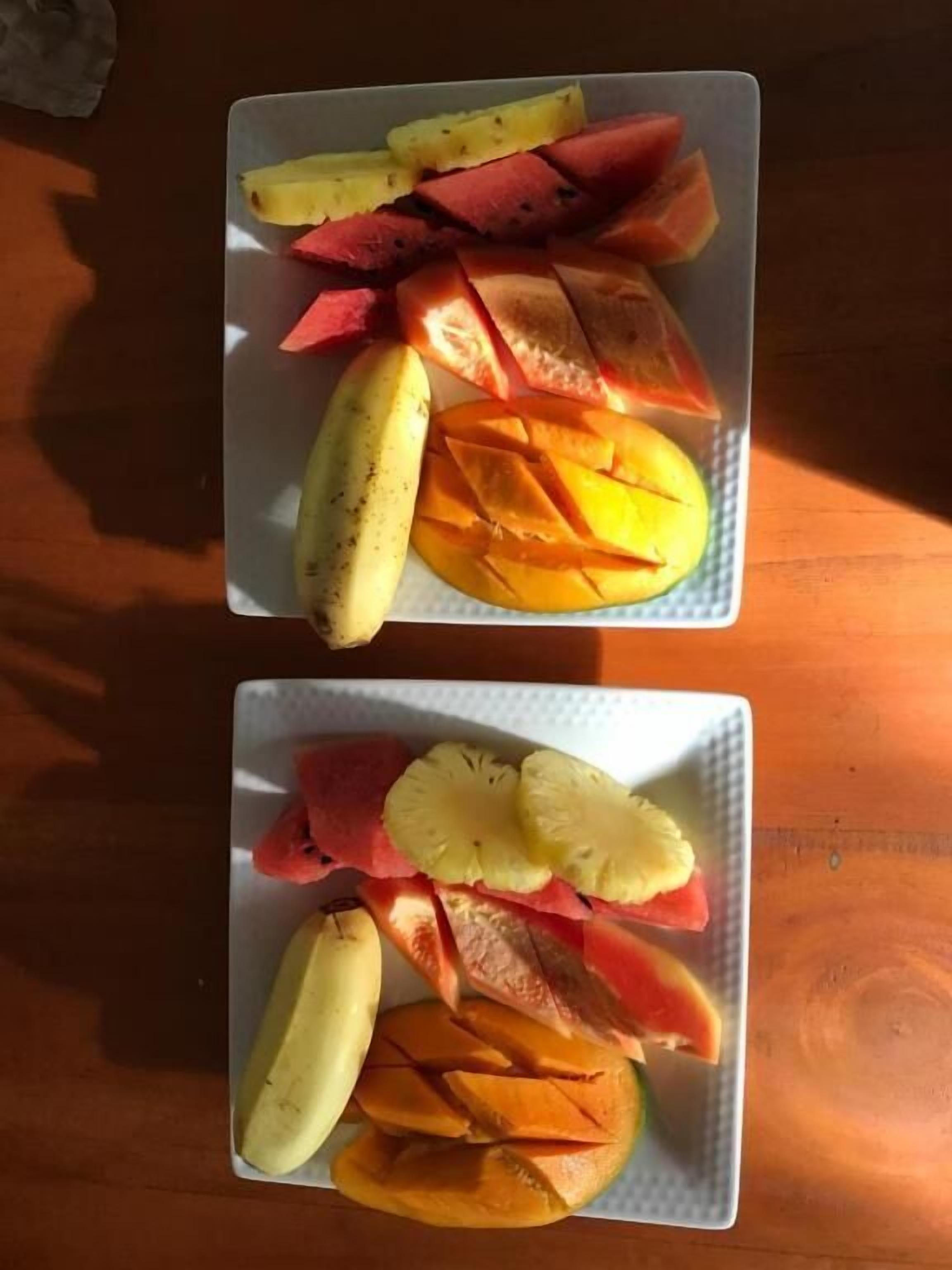 Duas travessas de frutas fatiadas sobre uma mesa de madeira.