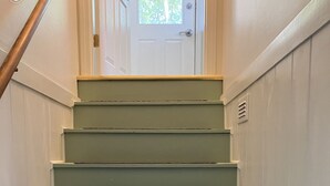 A staircase with light green steps and brown risers, leading to a white door with a window above it.