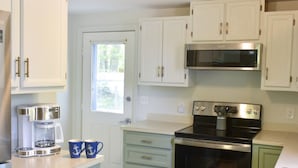 A kitchen with white cabinets, a stainless steel stove, and a coffee maker.