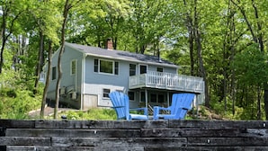 A two-story house with a balcony, surrounded by trees.