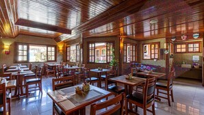 A restaurant with wooden tables and chairs, large windows, and a brick wall. - Pousada Saint Gallen  (Campos do Jordão)