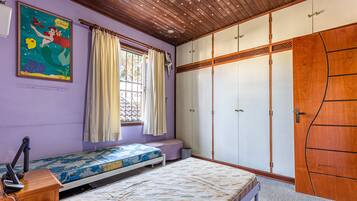 A bedroom with a bed, a window with curtains, a wardrobe, and a poster on the wall.