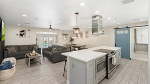 Una cocina moderna con una isla central, horno empotrado y comedor con mesa y sillas.