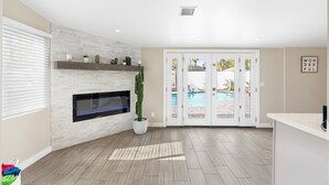 Amplia sala de estar con chimenea, vista a la piscina a través de puertas de vidrio y un diseño moderno.