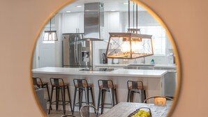 Una cocina moderna con una isla central, taburetes de bar y una mesa de comedor.