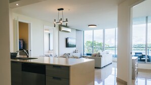 A modern kitchen with a central island, a dining area with a sofa, and large windows offering a view. - Apartment in Casa Bonita (Veracruz)