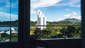 A view from a window with a balcony, overlooking a tall white building, lush greenery, and a mountain range. - Apartment in Casa Bonita (Veracruz)
