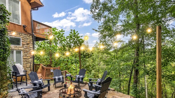 An outdoor patio with Adirondack chairs, a fire pit, and string lights. - Helen Lodge with Sauna and Hot Tub, 2 min to Helen (Helen)