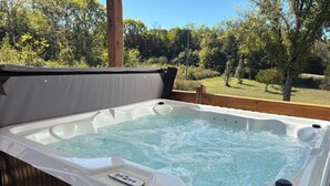 A hot tub with a wooden deck and a view of a grassy area with trees. - Family Farmhouse (Watertown)