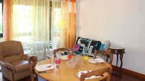 A dining area with a round table set for two, a leather armchair, and a sofa with a colorful blanket. - One-bedroom flat with terrace and parking space, 400 metres from the port - 4RS207 (SAINT CYPRIEN PLAGE)