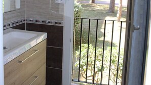 A bathroom with a large mirror, a sink, and a toilet. There is a window with a view of trees and a fence. - One-bedroom flat with terrace and parking space, 400 metres from the port - 4RS207 (SAINT CYPRIEN PLAGE)
