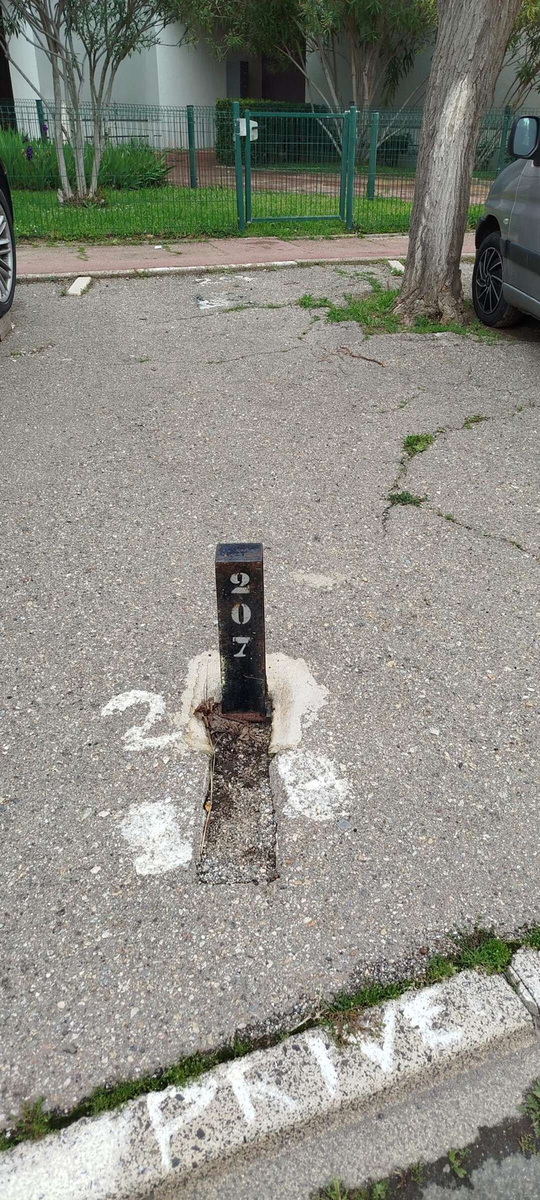 A parking meter with the number 2017 on a street with a 'PARKING' sign visible.
