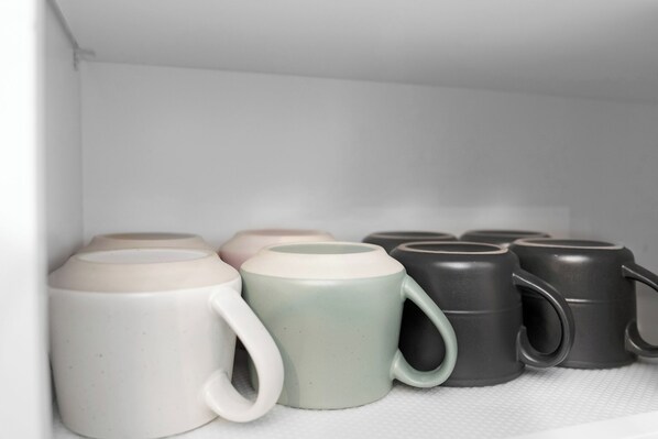 Una repisa con varios tazas de cerámica en diferentes colores.