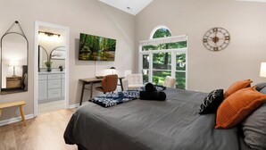 Ein Schlafzimmer mit Bett, Schreibtisch, Stuhl, Fenster und einer Wanduhr.