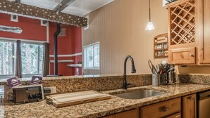Eine Küche mit Granit Arbeitsplatten, Holzschränken, einer Spüle und einem Weinkühlschrank.
