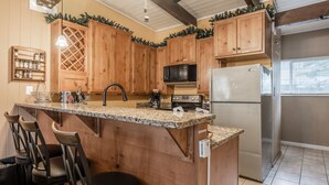 Eine Küche mit Holzschränken, einer Granit Arbeitsplatte, einem Edelstahlkühlschrank und einer Mikrowelle.