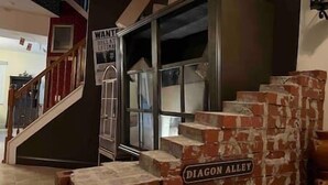 Portaikko, jonka yläpuolella on kyltti, jossa lukee ”DIAGON ALLEY”, johtaa huoneeseen, jossa on suuri ikkuna ja seinällä etsintäkuulutus.