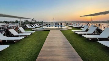 Una piscina techada, una piscina al aire libre, sombrillas