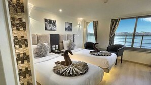 A hotel room with two beds, a view of the sea, and a modern design. - Nile Cruise Aswoan & Luxor 3 & 4 Nights (Aswan)