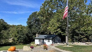 Une petite maison avec un mur en pierre et un mât sur lequel flotte un drapeau américain.