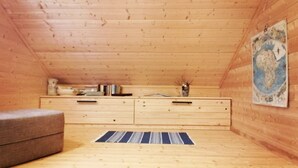 A wooden cabin room with a sofa, a dresser, and a map on the wall. - Stylish 2 Bdr. cottage, with sauna and all the necessary commodities (Österhankmo)