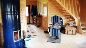 A wooden interior with a staircase, a blue barrel stove, and a cozy seating area. - Stylish 2 Bdr. cottage, with sauna and all the necessary commodities (Österhankmo)