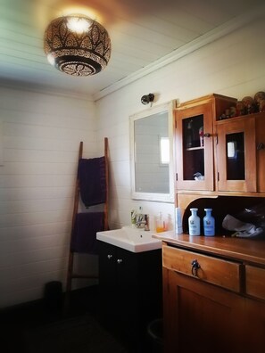 A bathroom with a wooden cabinet, a mirror, and a hanging towel rack. - Stylish 2 Bdr. cottage, with sauna and all the necessary commodities (Österhankmo)
