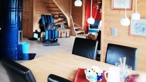 A wooden interior with a dining table, chairs, and a hanging light fixture. - Stylish 2 Bdr. cottage, with sauna and all the necessary commodities (Österhankmo)