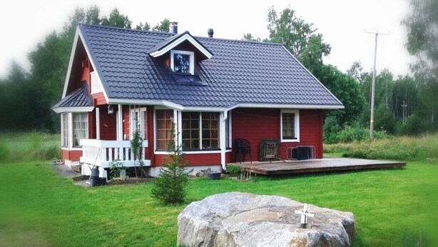 A red house with a dark roof, a porch, and a large rock in front. - Stylish 2 Bdr. cottage, with sauna and all the necessary commodities (Österhankmo)