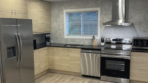 A modern kitchen with wooden cabinets, stainless steel appliances, and a window with blinds. - One of the kind fully loaded house located walking distance from cozy lake (Albrightsville)
