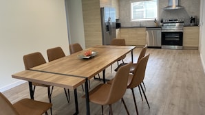A modern kitchen with a wooden dining table, chairs, and a stainless steel refrigerator. - One of the kind fully loaded house located walking distance from cozy lake (Albrightsville)