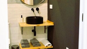 Ein Badezimmer mit einem runden Spiegel, einem schwarzen Waschbecken, einem Handtuchhalter und einer Toilette.