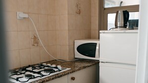 Eine kompakte Küche mit Gaskochfeld, Mikrowelle und weißem Kühlschrank.