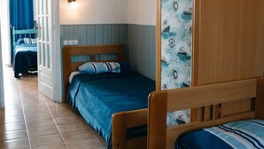 Ein Schlafzimmer mit zwei Einzelbetten, einem Holzschrank und einer Tür zu einem anderen Raum.