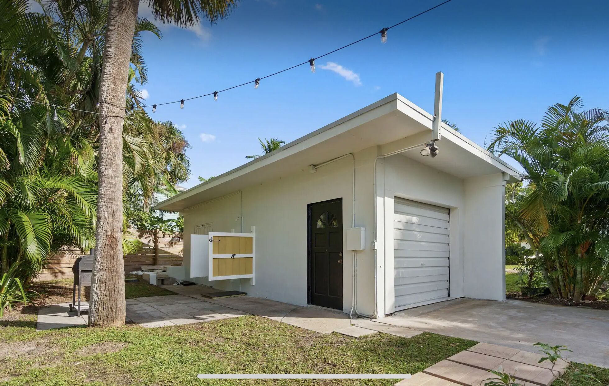 A small, single-story building with a garage, a door, and a small porch area.